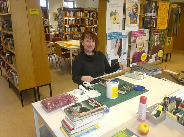 Die Freiwillige repariert Bücher in der Bibliothek, bei der sie hospitiert.