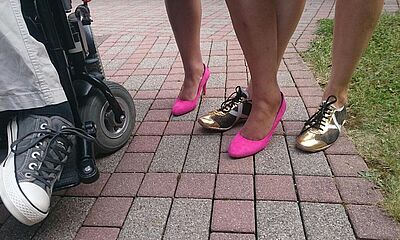 Drei Paar Füße in Turnschuhen, pinke Pumps und goldenen Halbschuhen.