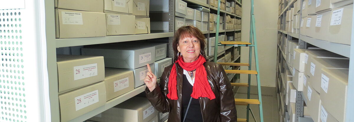 Die Freiwillige steht zwischen den hohen Regalen des Archivs.