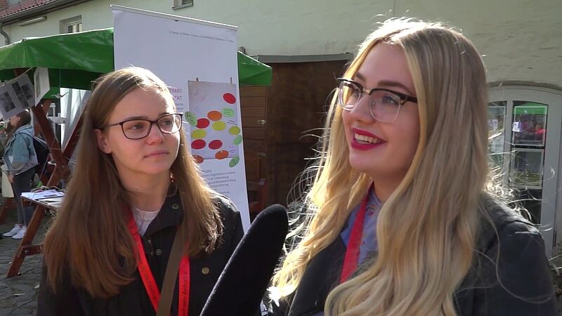 OK Magdeburg  Zwei junge, weiße Frauen mit Brillen werden interviewt. Standbild aus dem Youtube-Video Auf- und Abgesang, das oben verlinkt ist.