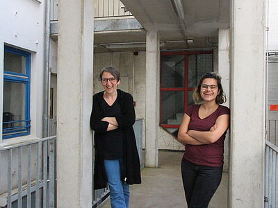 Paulina Güllü und Susanne Tod stehend lachend auf einer Terrasse.